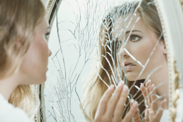 mujer frente a espejo roto sin autoestima